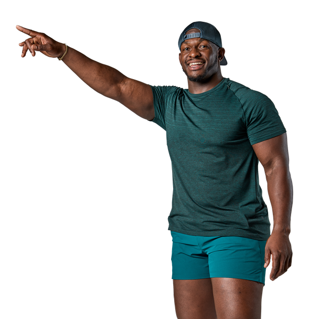 A man in a green shirt and blue shorts is pointing at something.