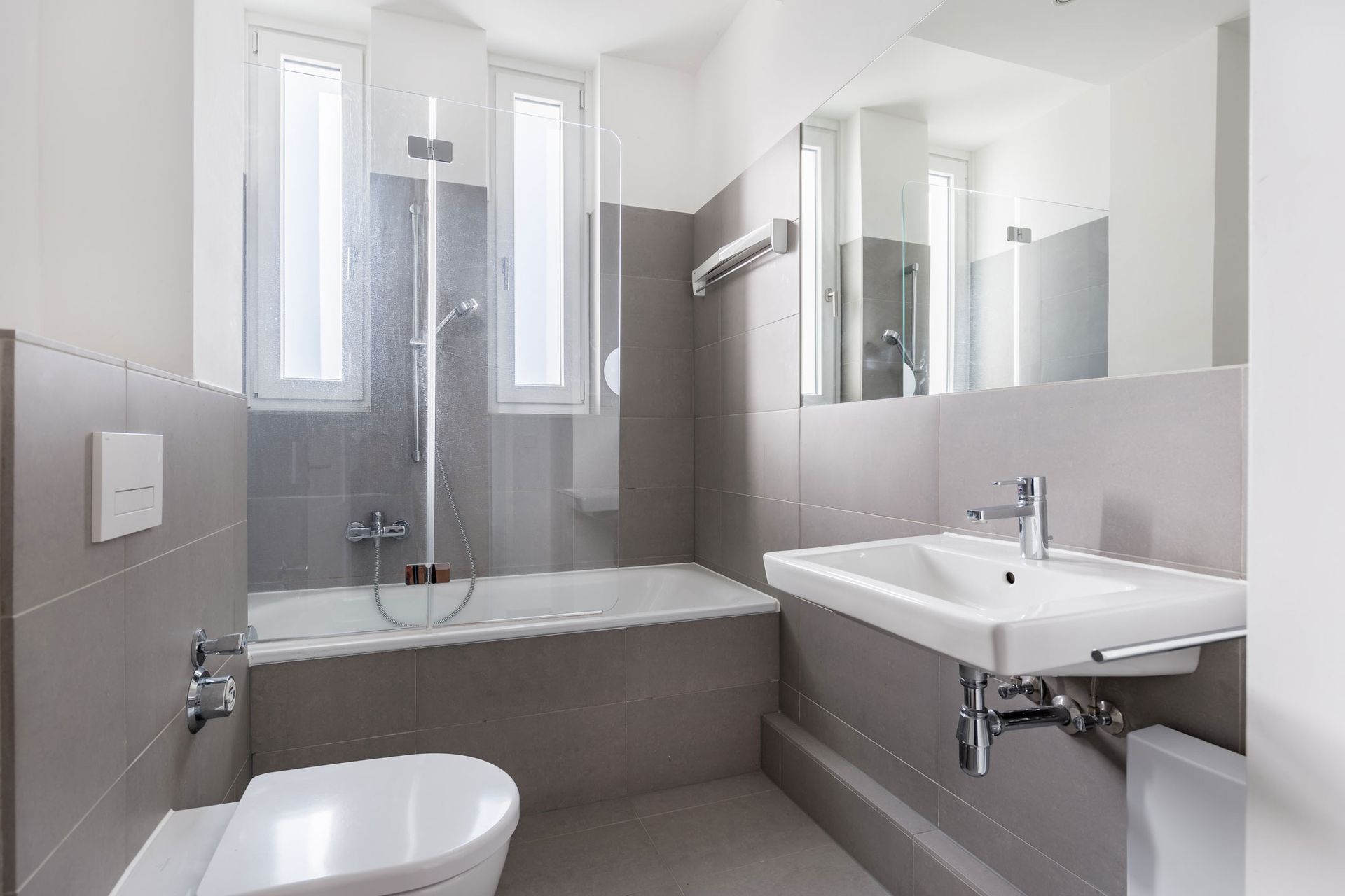 A bathroom with a toilet, sink, bathtub and mirror.