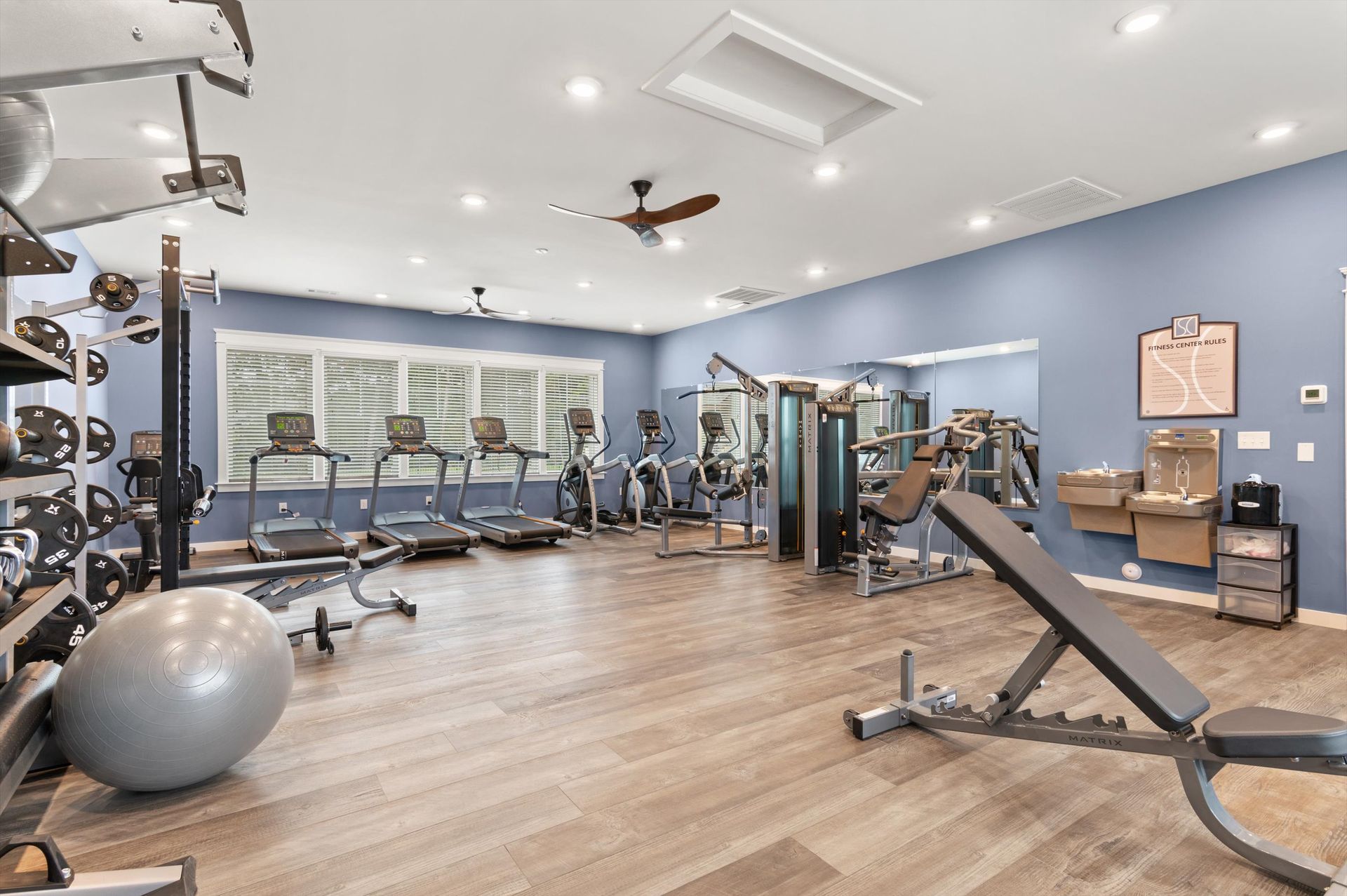 A large gym with a lot of equipment and a ceiling fan.