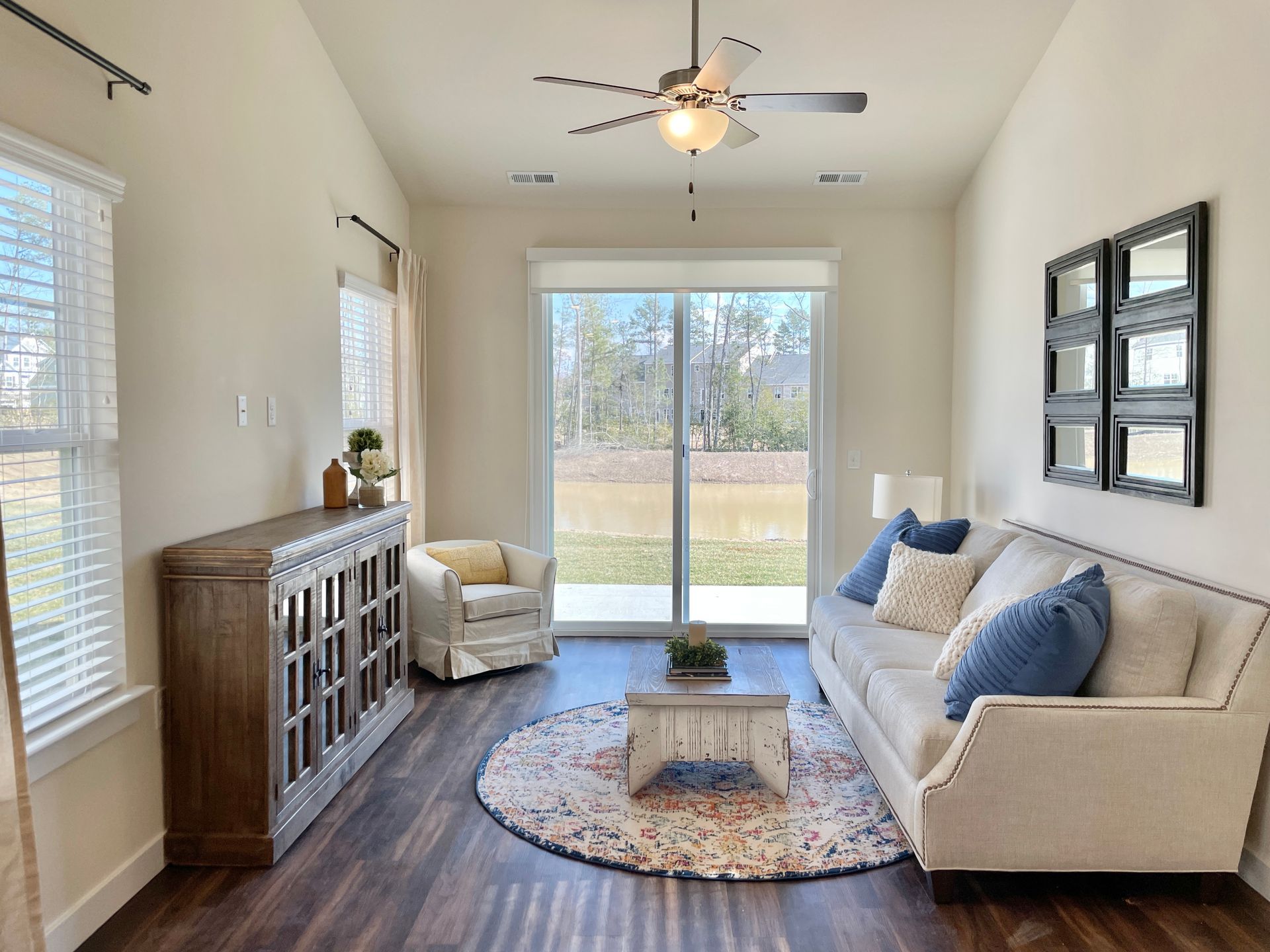 A living room with a couch , chair , coffee table and ceiling fan.