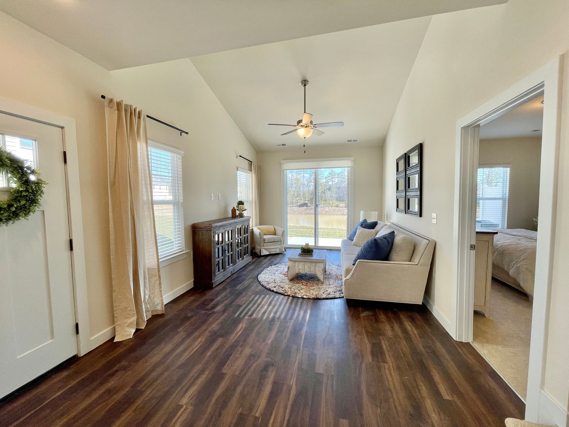 A living room with hardwood floors , a couch , and a ceiling fan.
