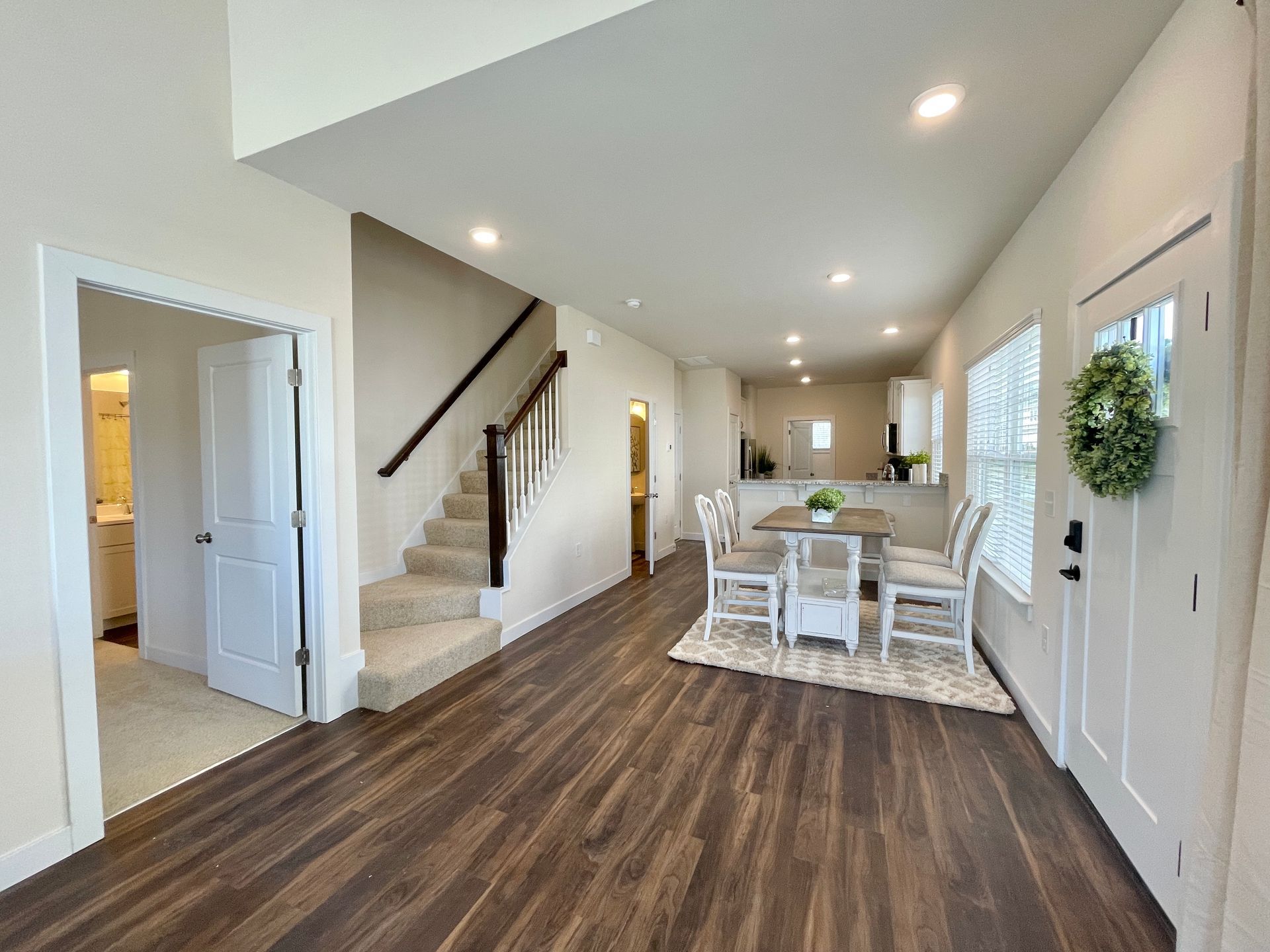 A living room with hardwood floors , stairs , a table and chairs.