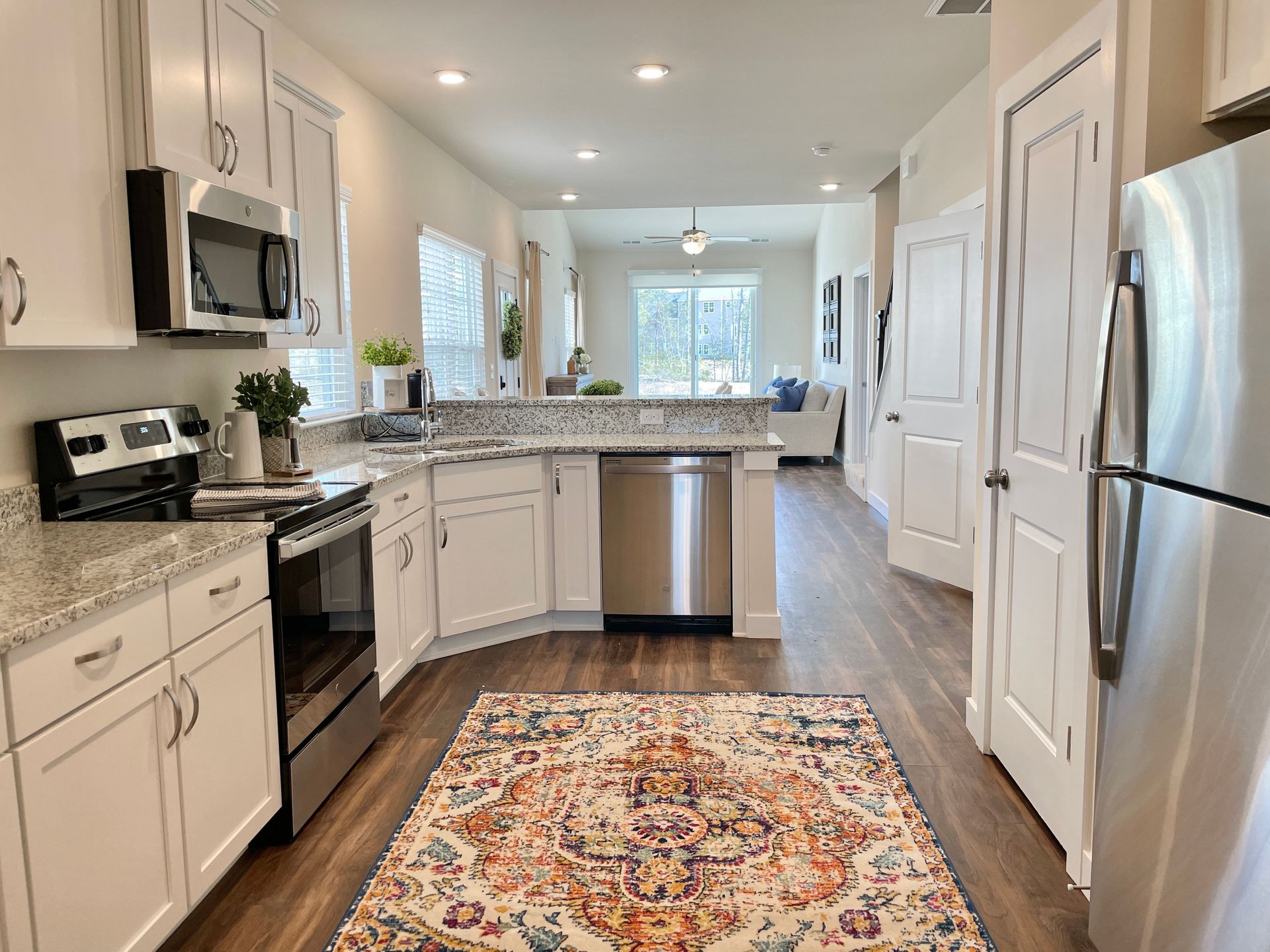 A kitchen with white cabinets and stainless steel appliances and a rug on the floor.