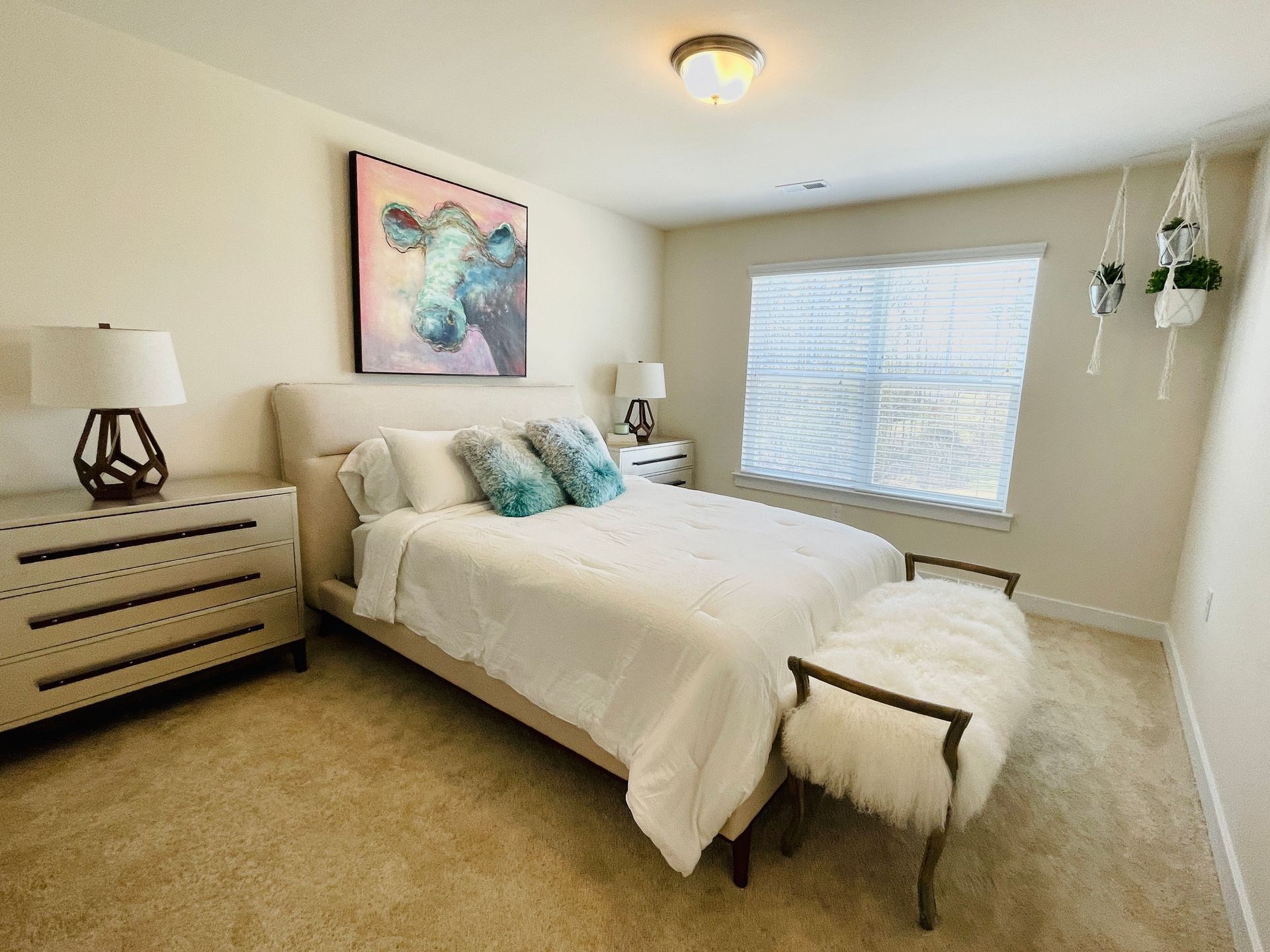 A bedroom with a bed , dresser , lamps , and a window.