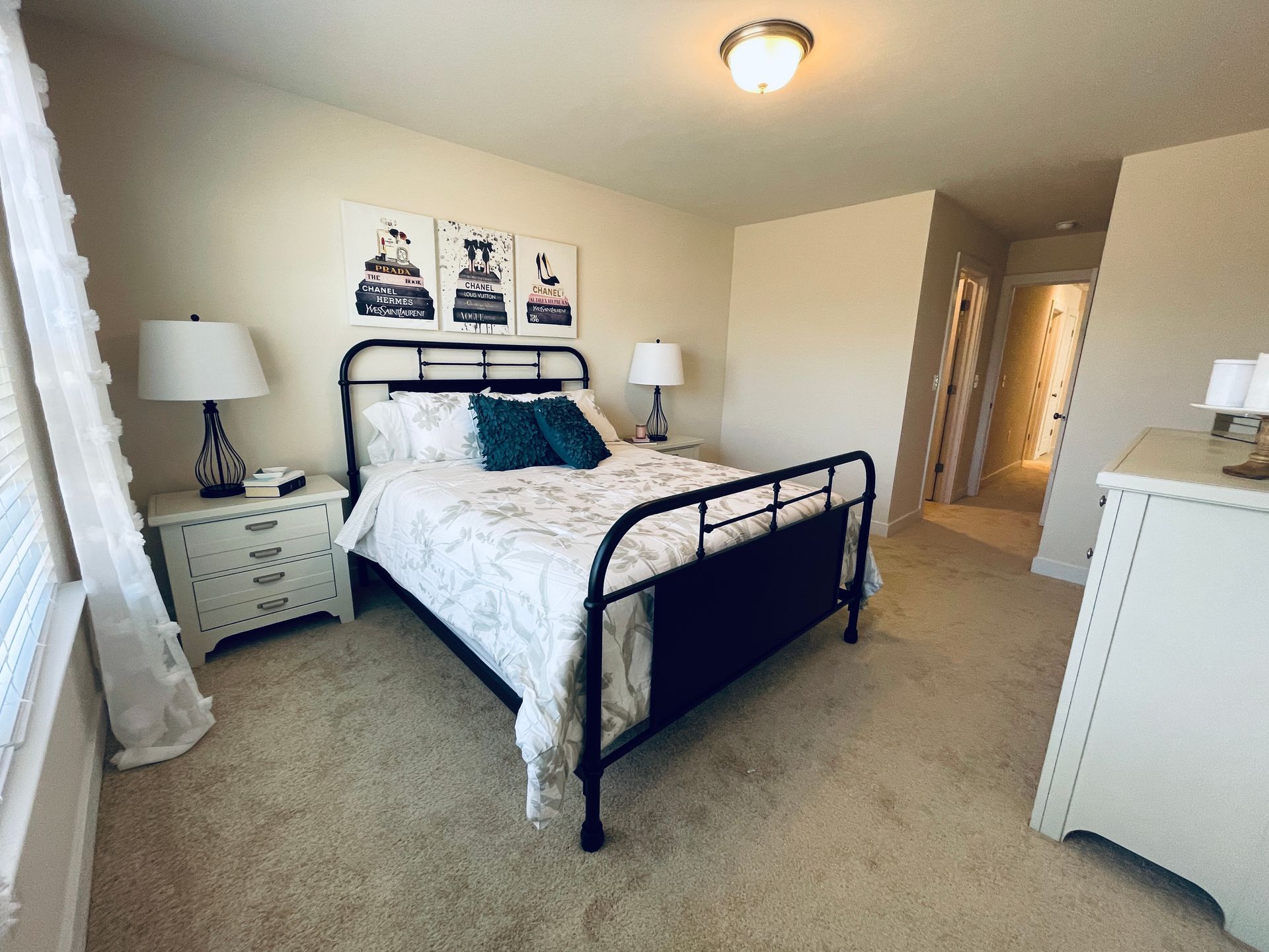 A bedroom with a bed , nightstand , dresser and lamps.