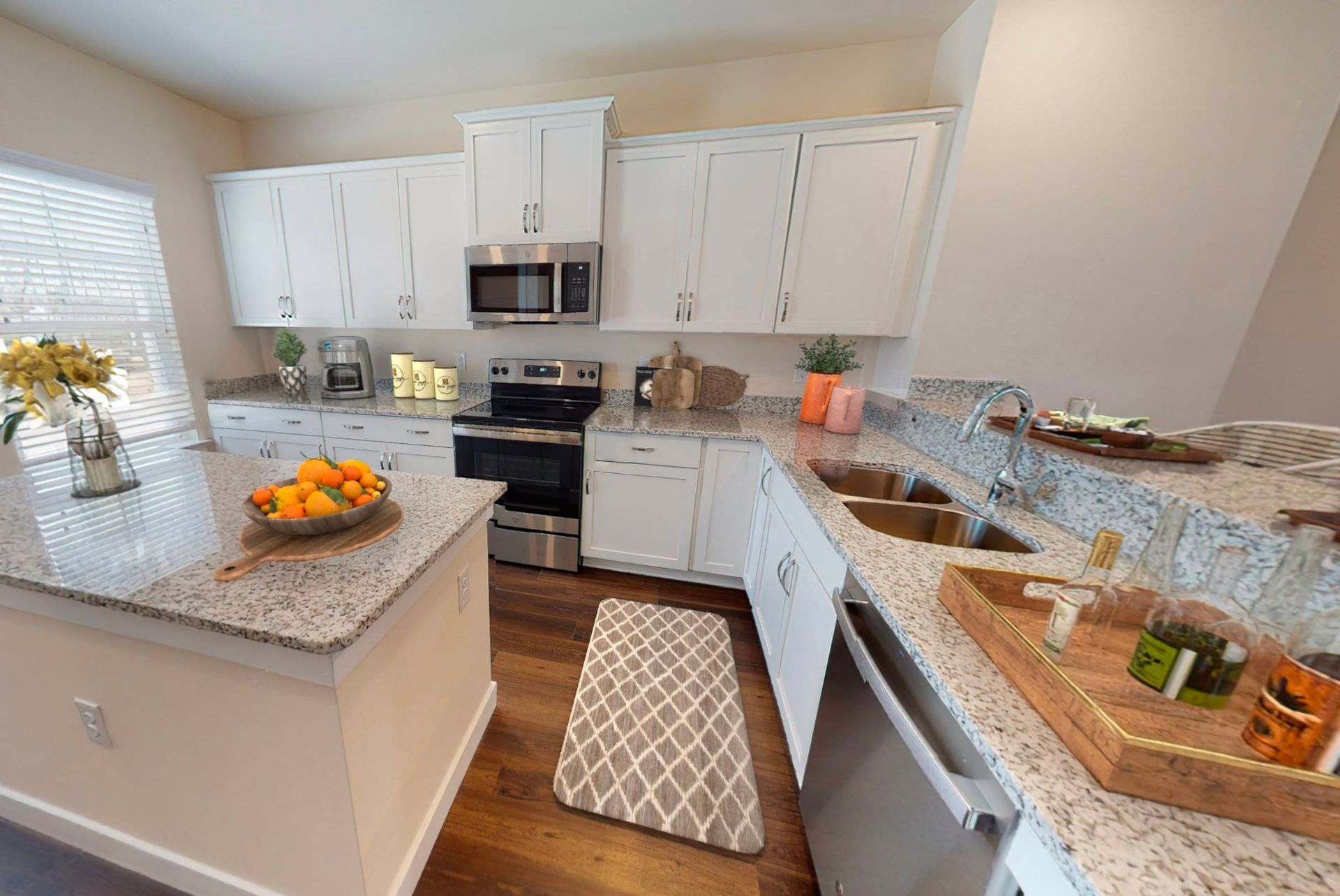 A kitchen with white cabinets , granite counter tops , stainless steel appliances and a large island.