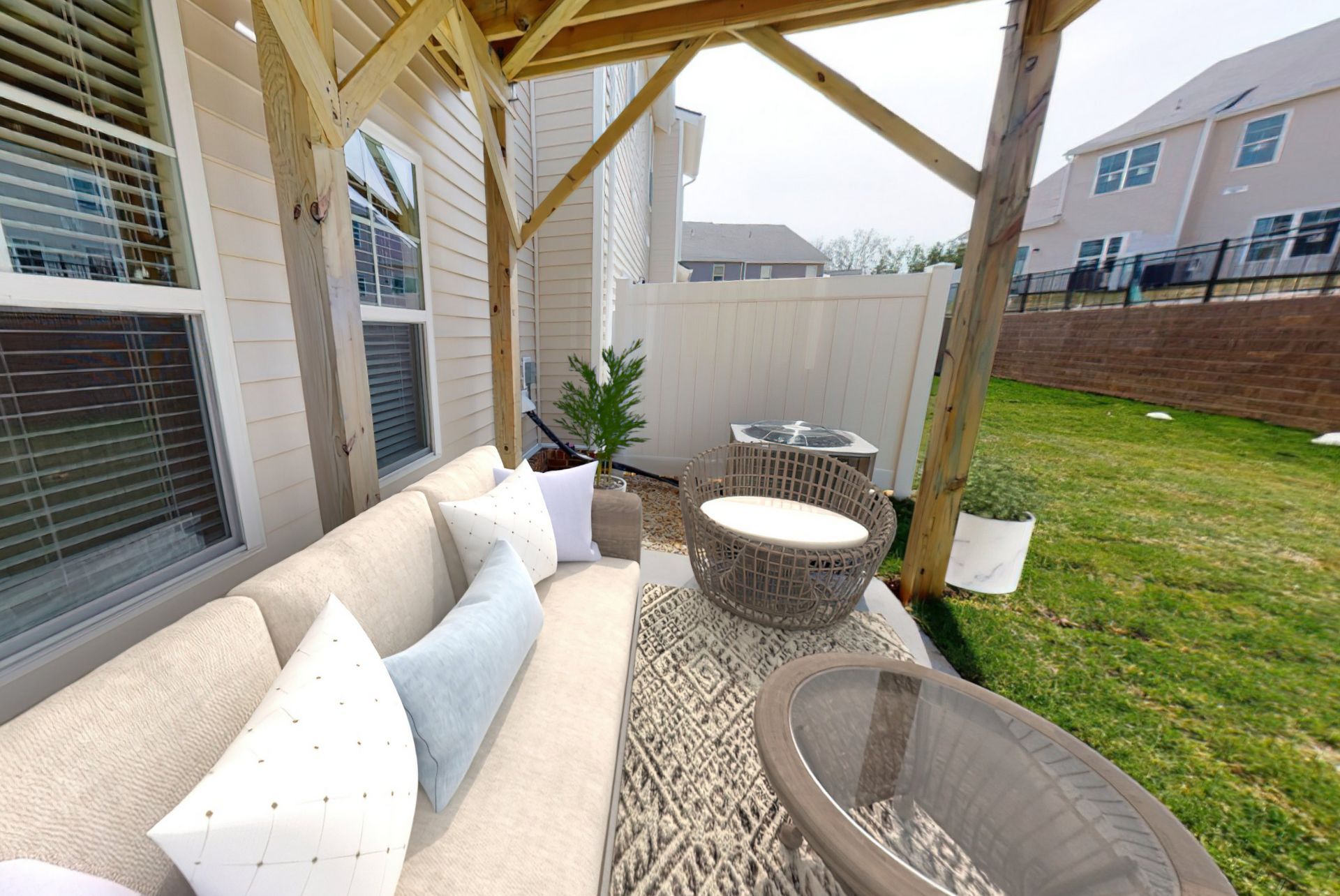 A patio with a couch , chairs and a table under a pergola.