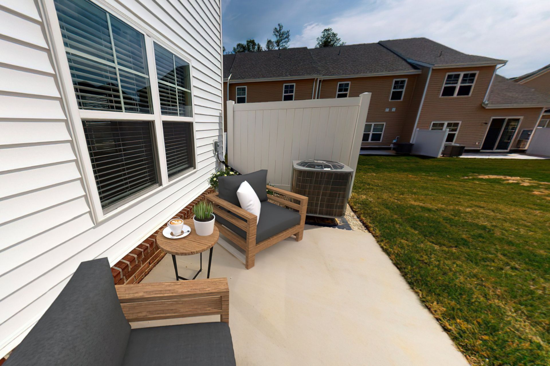 A patio with a chair and a table in front of a house.