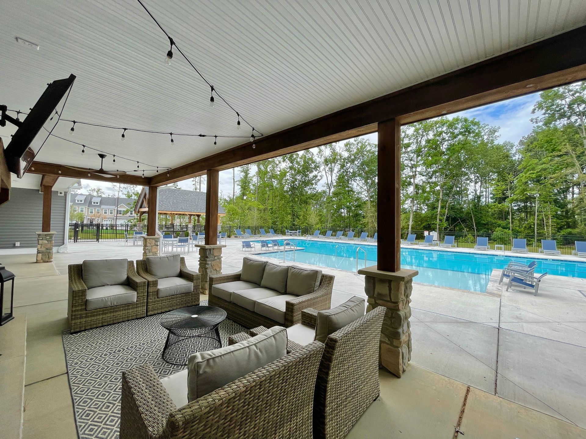 A patio with wicker furniture and a pool in the background.