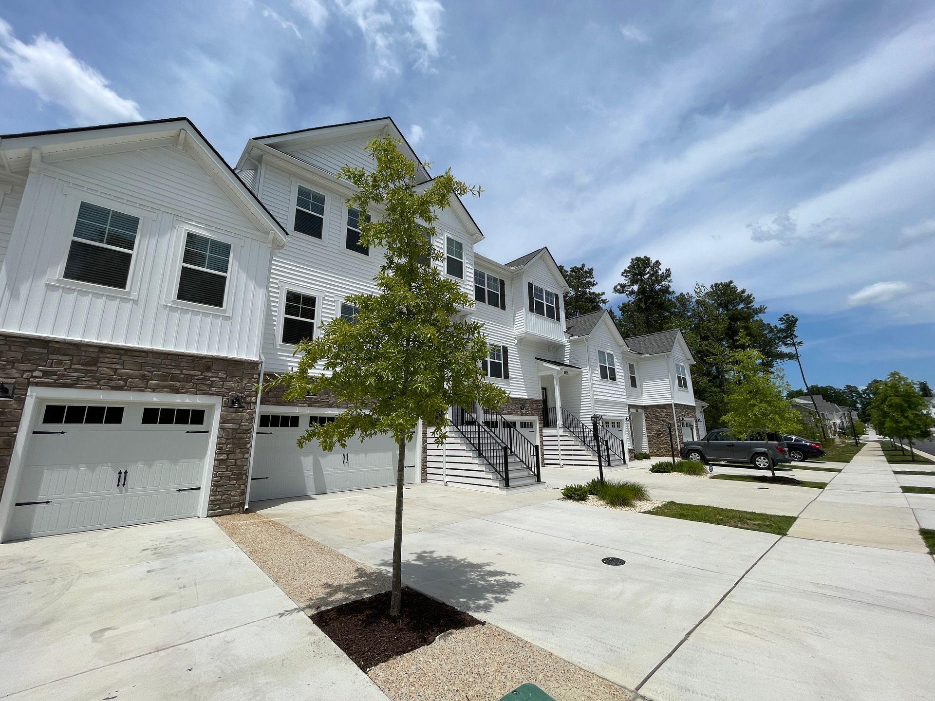 A row of white houses with garages in a residential area.
