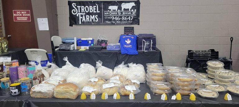 A market stall with baked goods and farm products. Strobel Farms sign is visible.