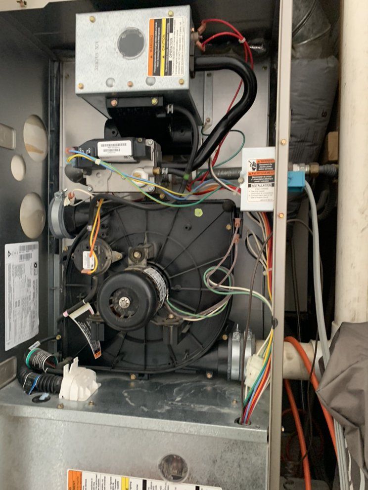 The inside of a heating system with a lot of wires coming out of it.