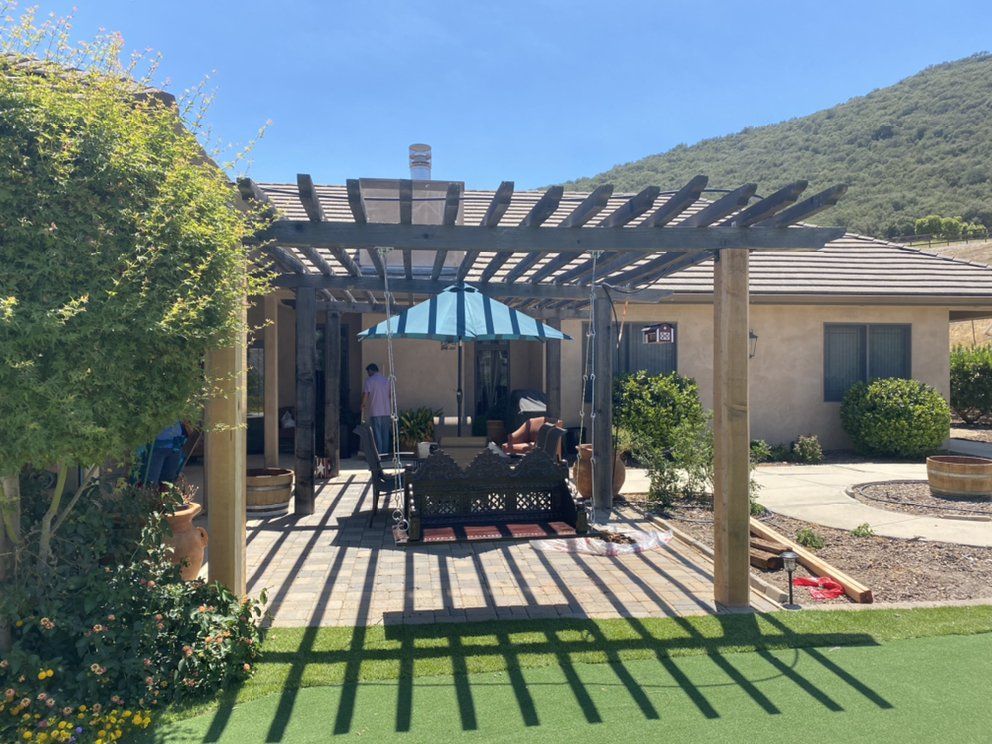 A pergola with a blue umbrella in front of a house
