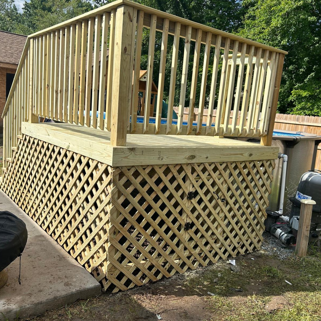 Wooden deck with latticework skirting, stairs, and railing surrounding a pool.