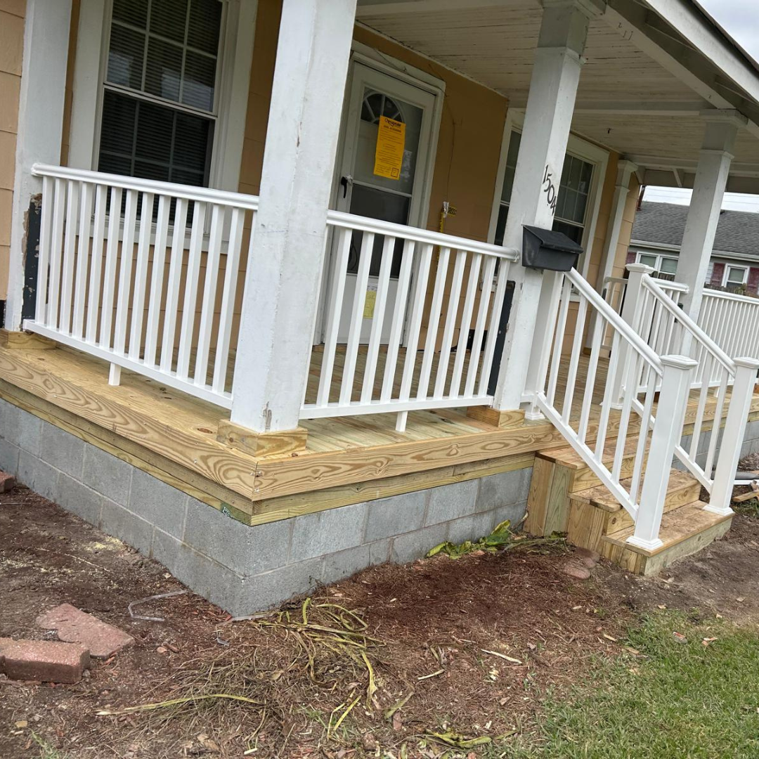Front porch with white railings, wooden steps, and cinder block base.