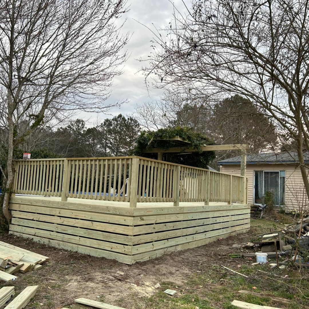 Wooden deck under construction in a backyard with a house visible.