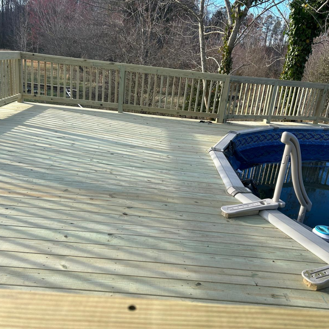 Wooden deck next to an above-ground pool with a blue cover. Sunny day, trees in background.