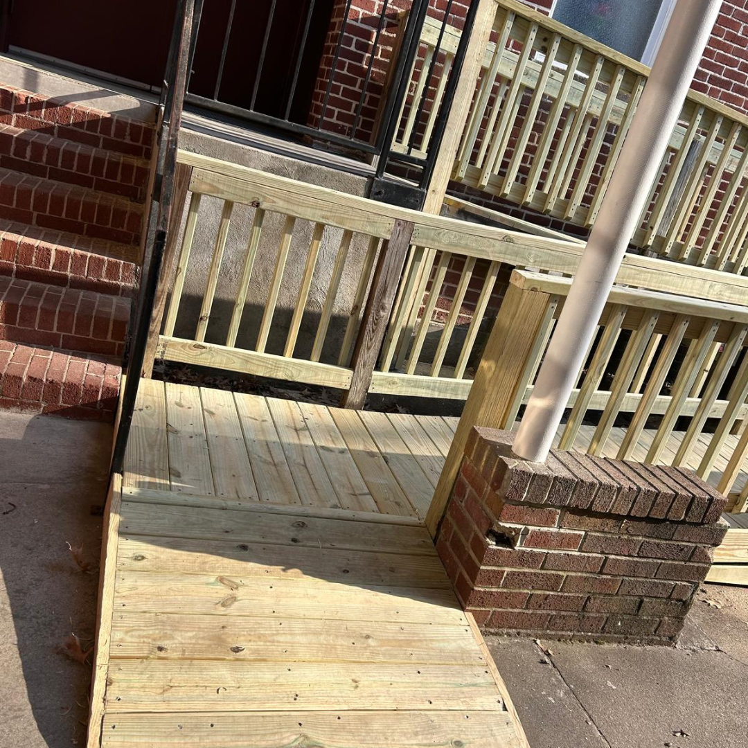 Wooden wheelchair ramp next to brick steps on a building exterior.