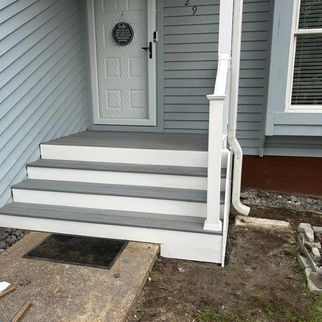 Light blue house with three gray steps, a white door, and a white railing.