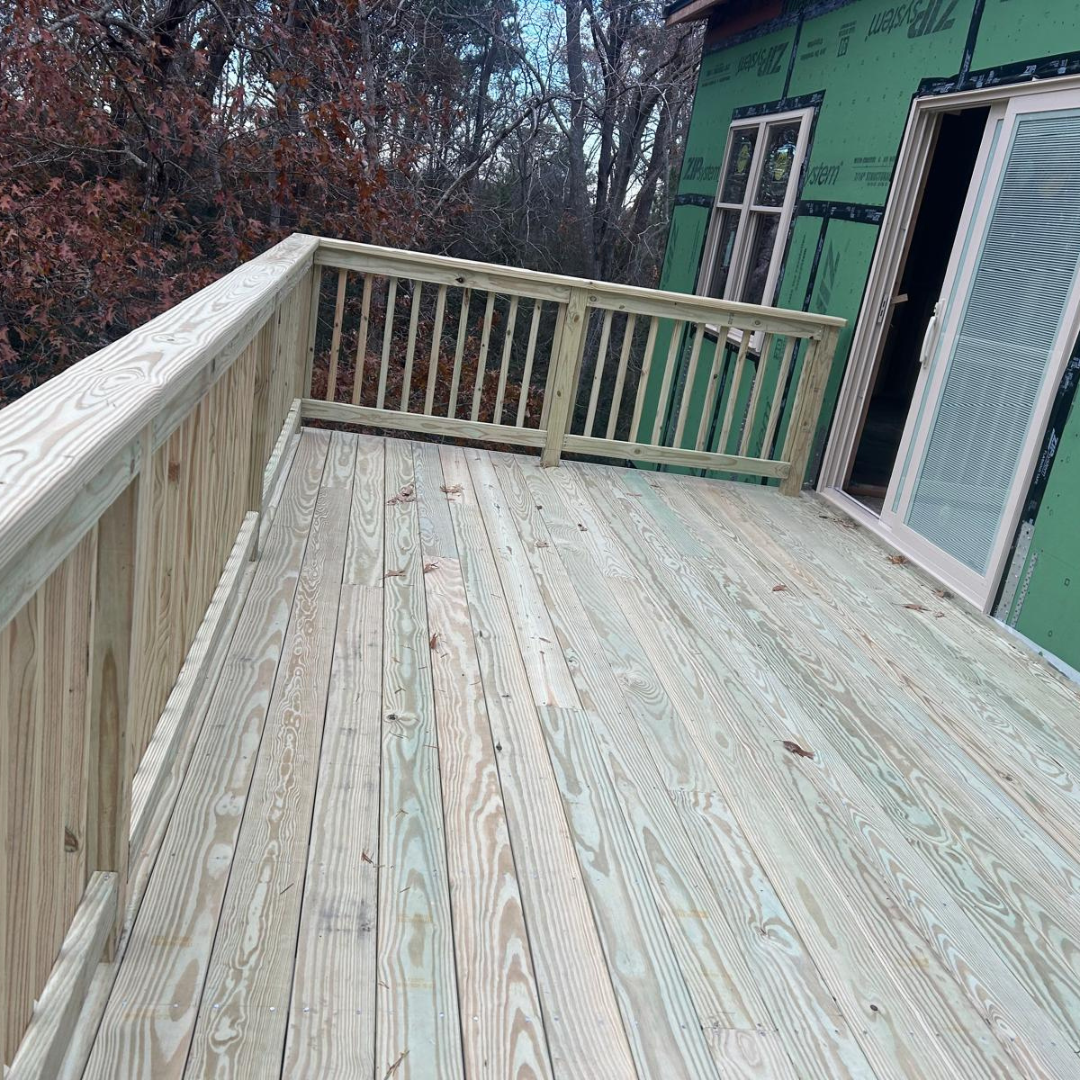 Wooden deck with railing, next to a building under construction.