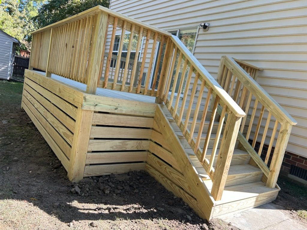 Wooden deck and steps leading to a house, with railings and a grassy yard.
