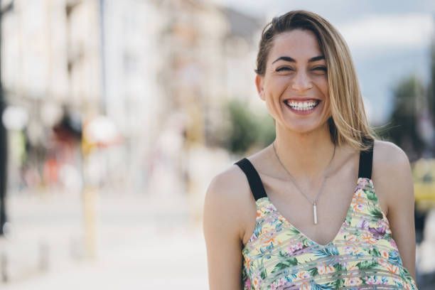 A woman in a floral dress is smiling and looking at the camera.