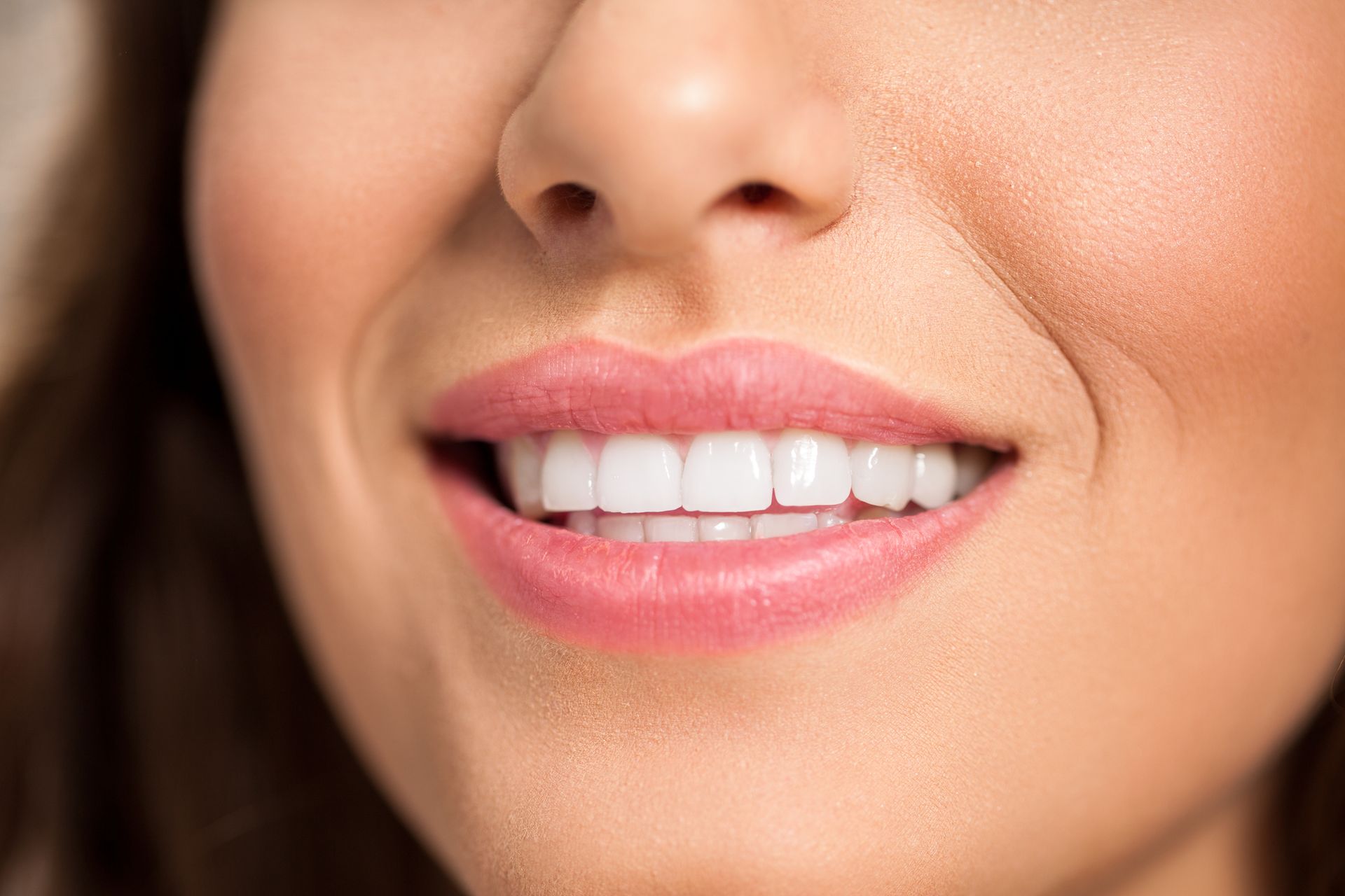 A close up of a woman 's mouth with white teeth and pink lips.