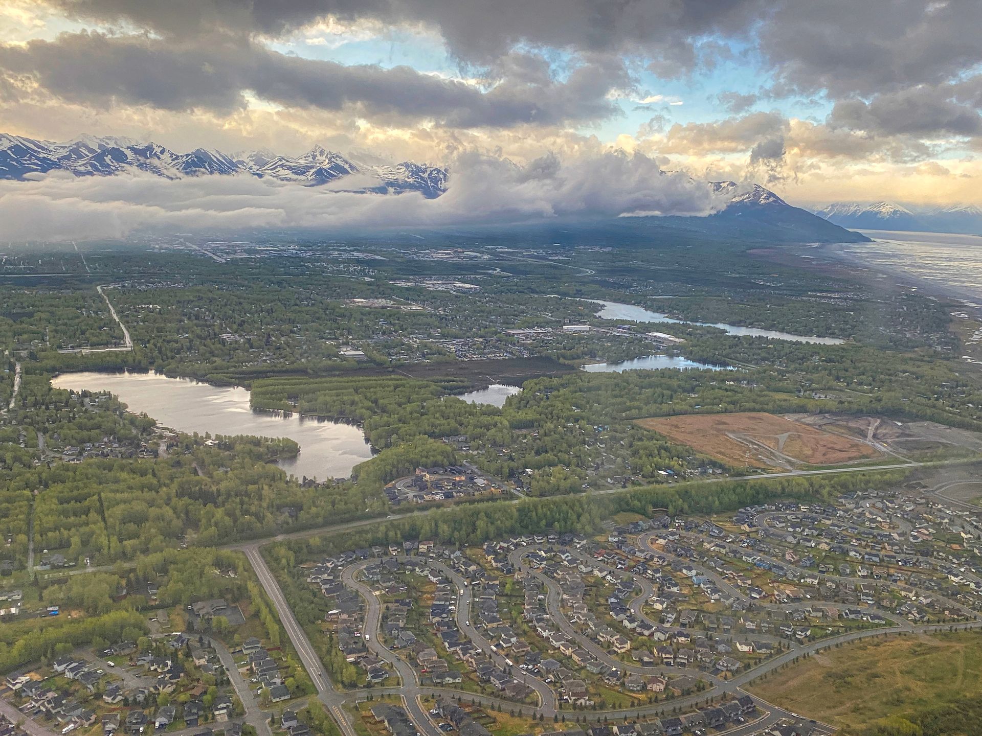 An aerial view of a city with a lake and mountains in the background.