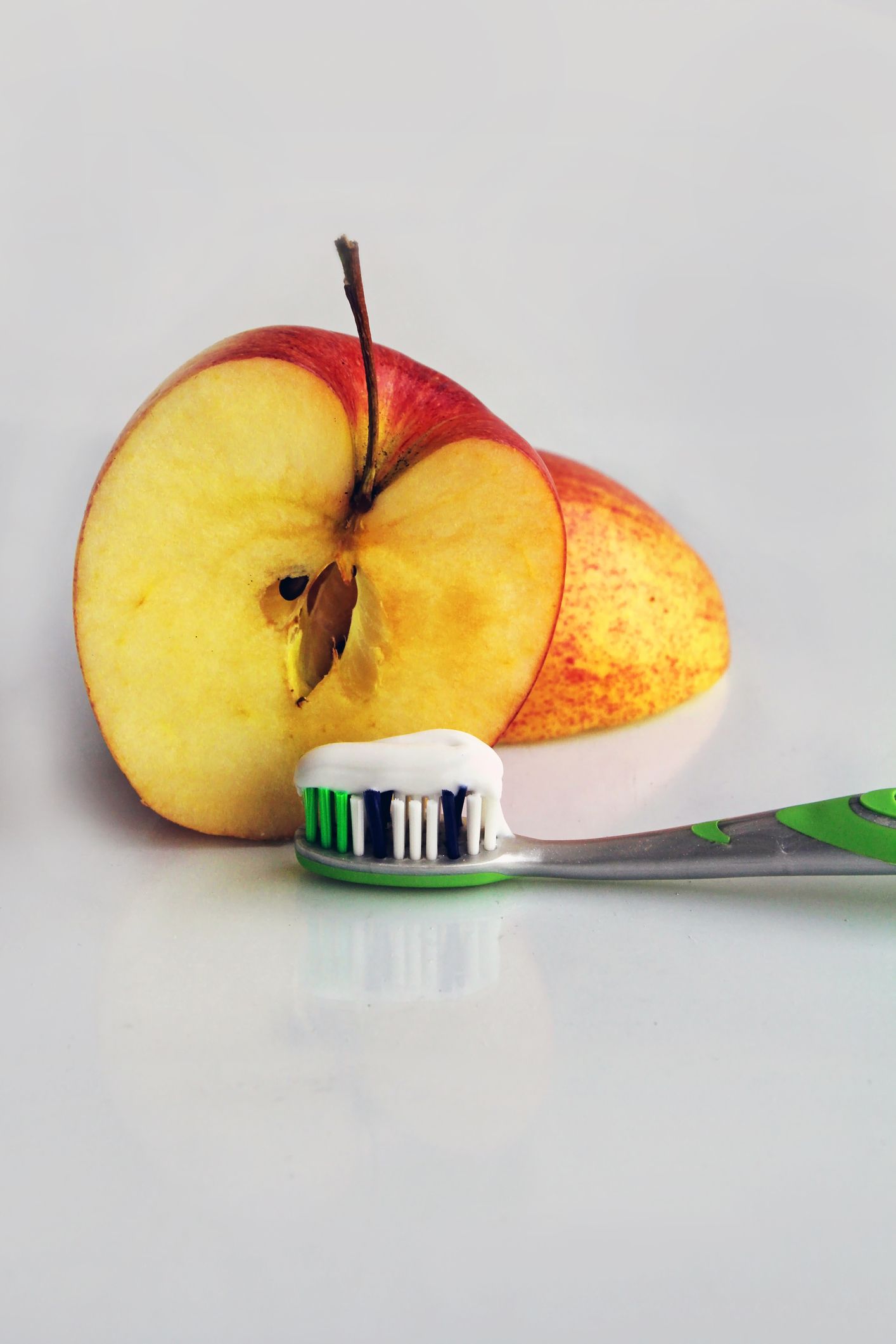 An apple and a toothbrush with toothpaste on it