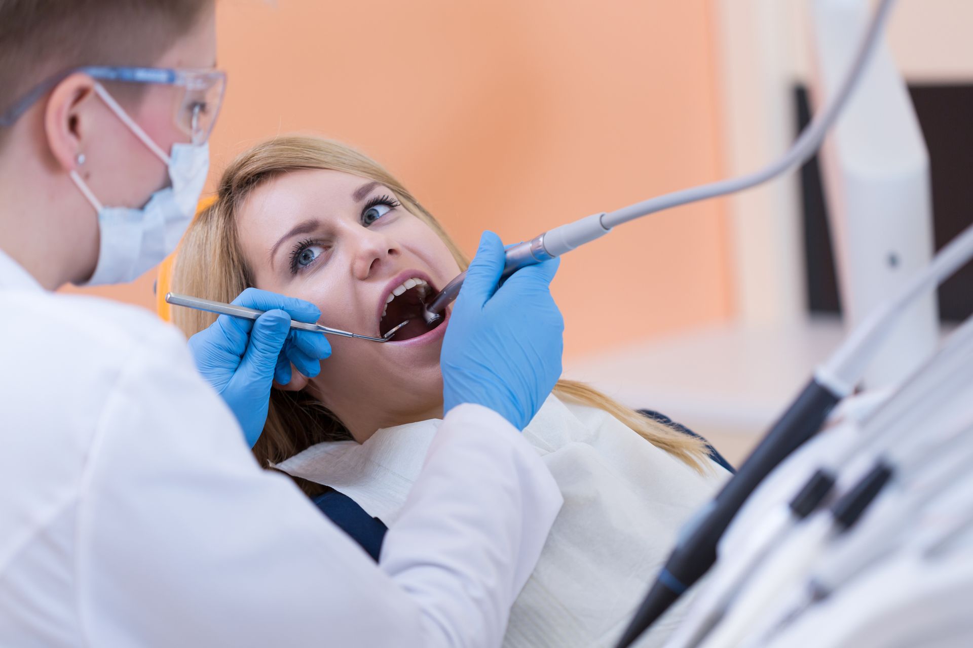A woman is getting her teeth examined by a dentist in a dental office.
