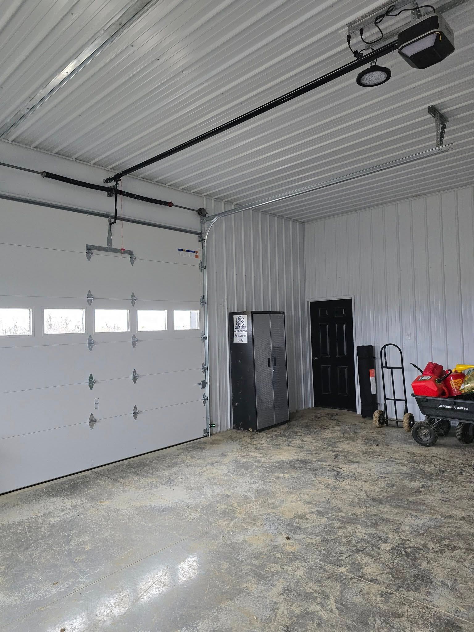 Inside of a garage with a closed white door, a black door, and a grey safe.