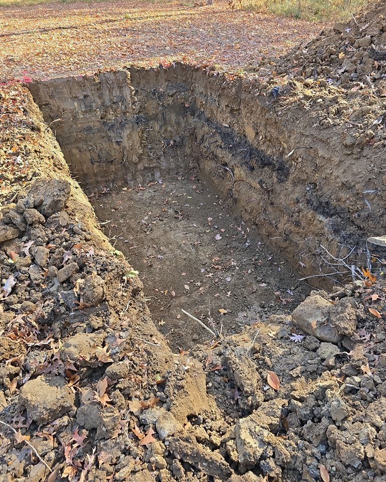 Rectangular excavation in brown soil, revealing a vertical cross-section.