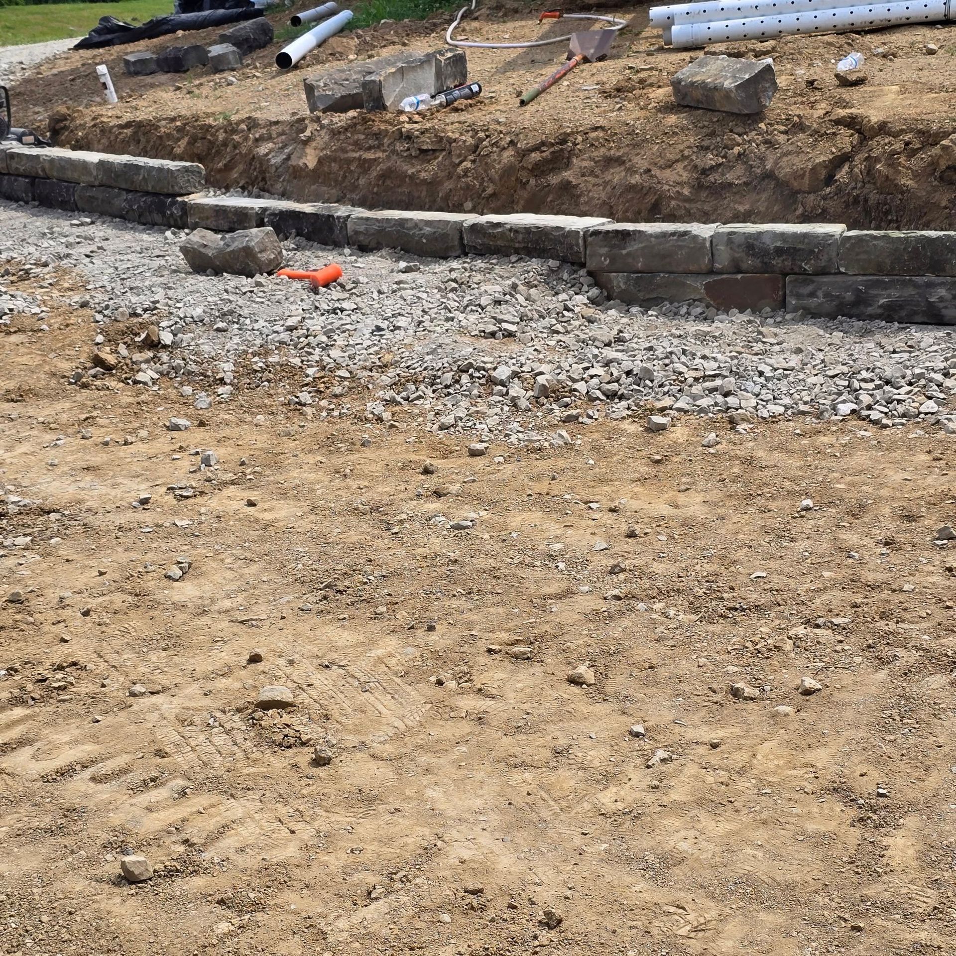 Construction site with retaining wall being built. Bricks, gravel, and dirt.