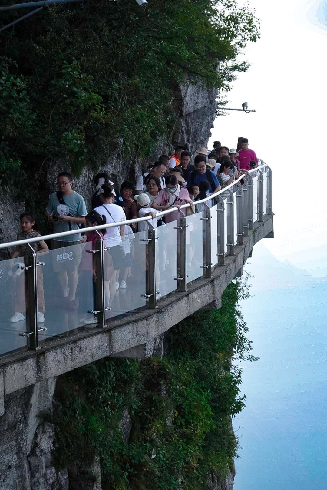 A group of people are standing on a bridge over a cliff.