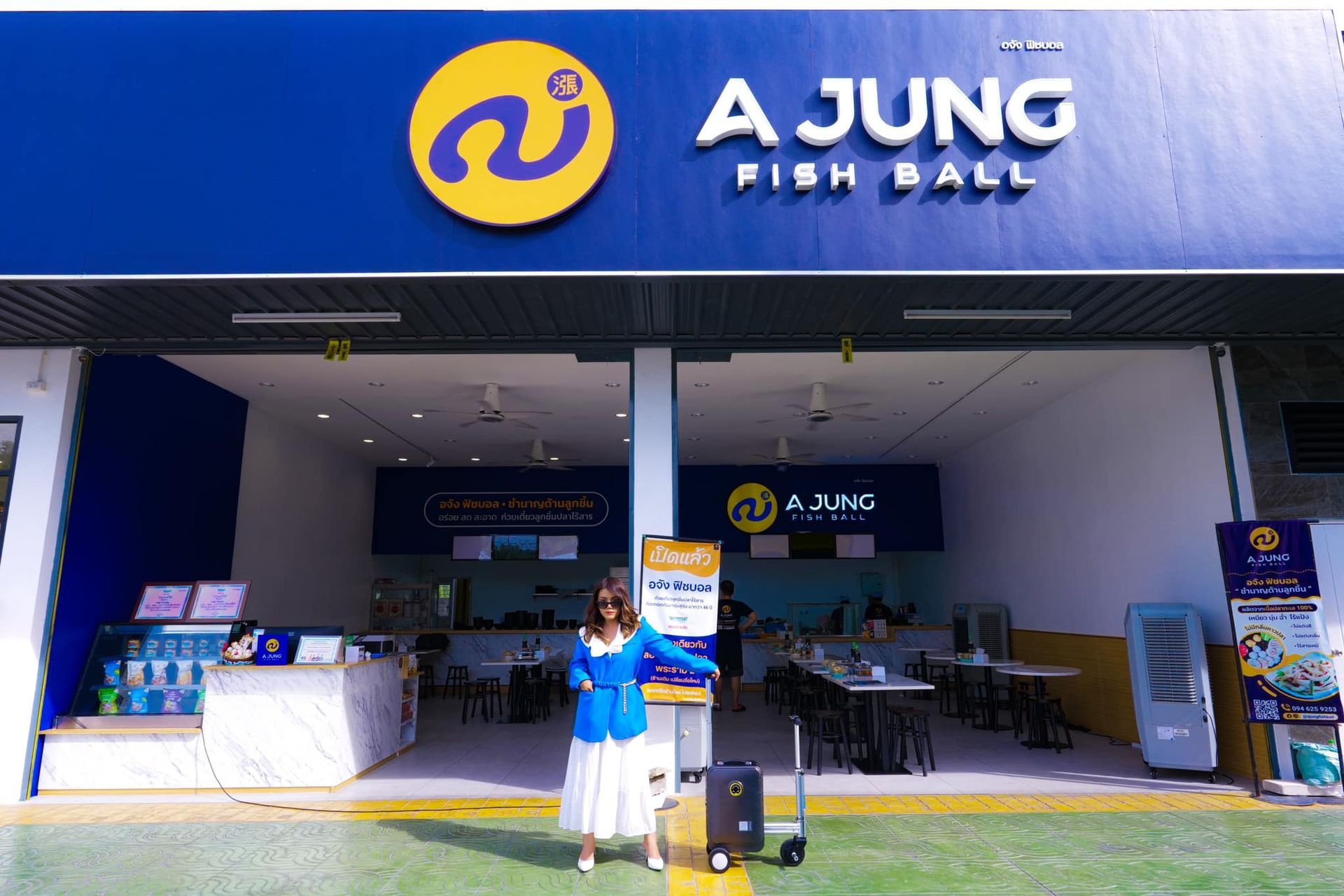 A woman is standing in front of a jung fish ball restaurant.