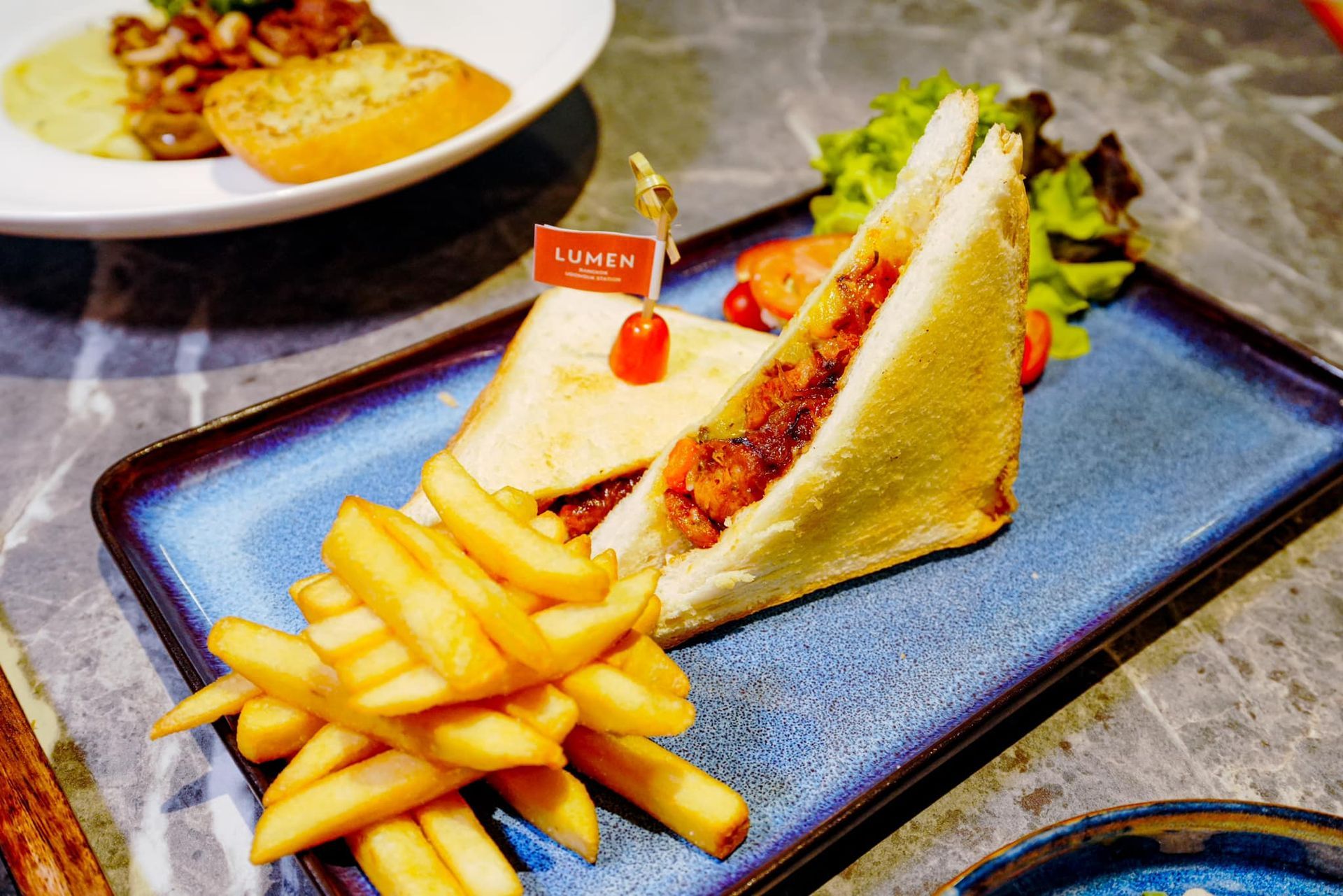 A sandwich and french fries on a blue plate on a table.
