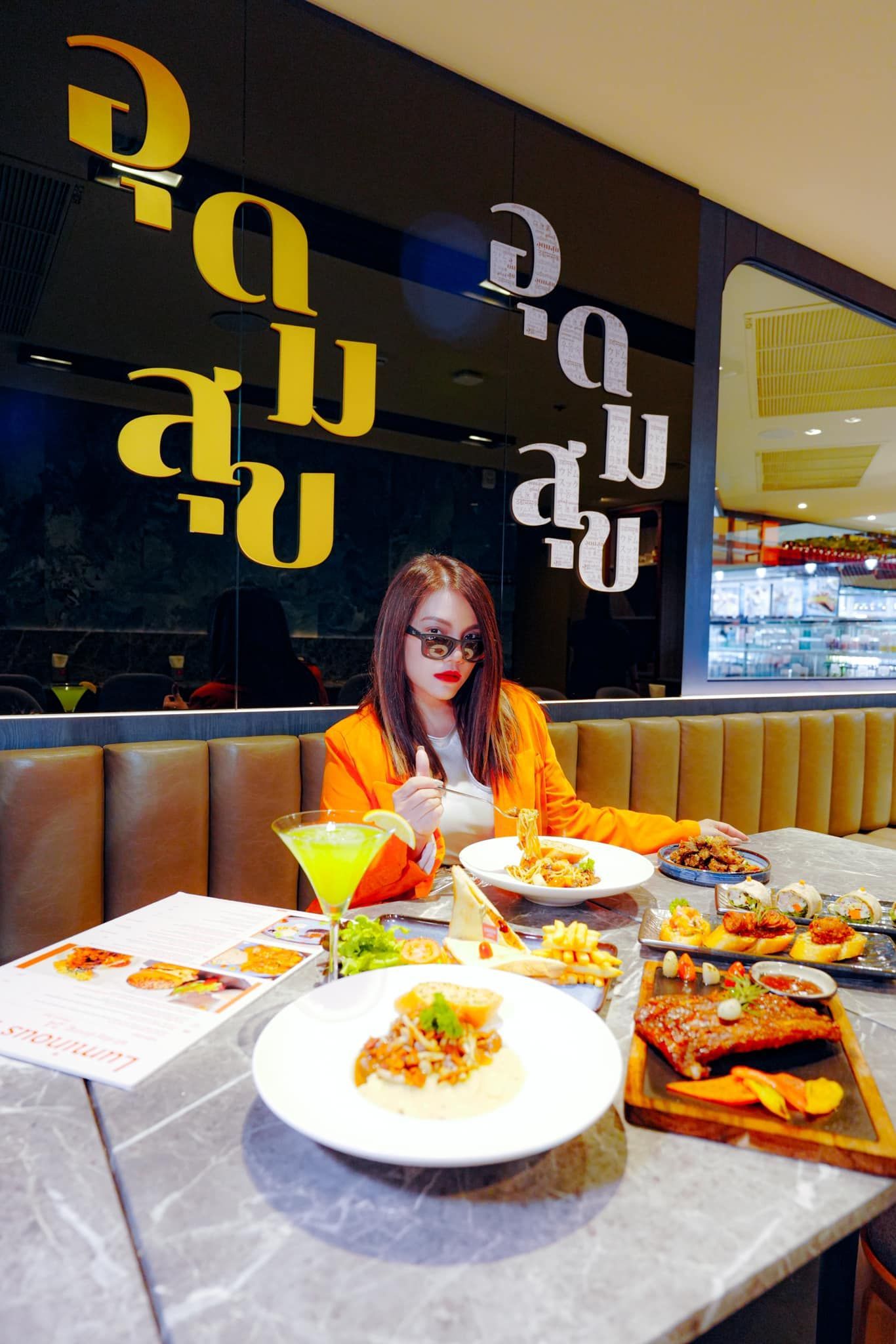 A woman is sitting at a table with plates of food.