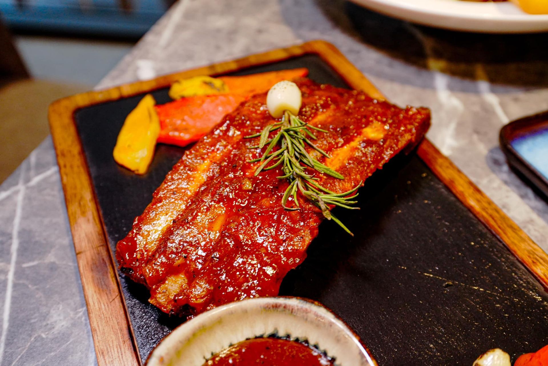 A close up of a plate of food with ribs and vegetables on a table.