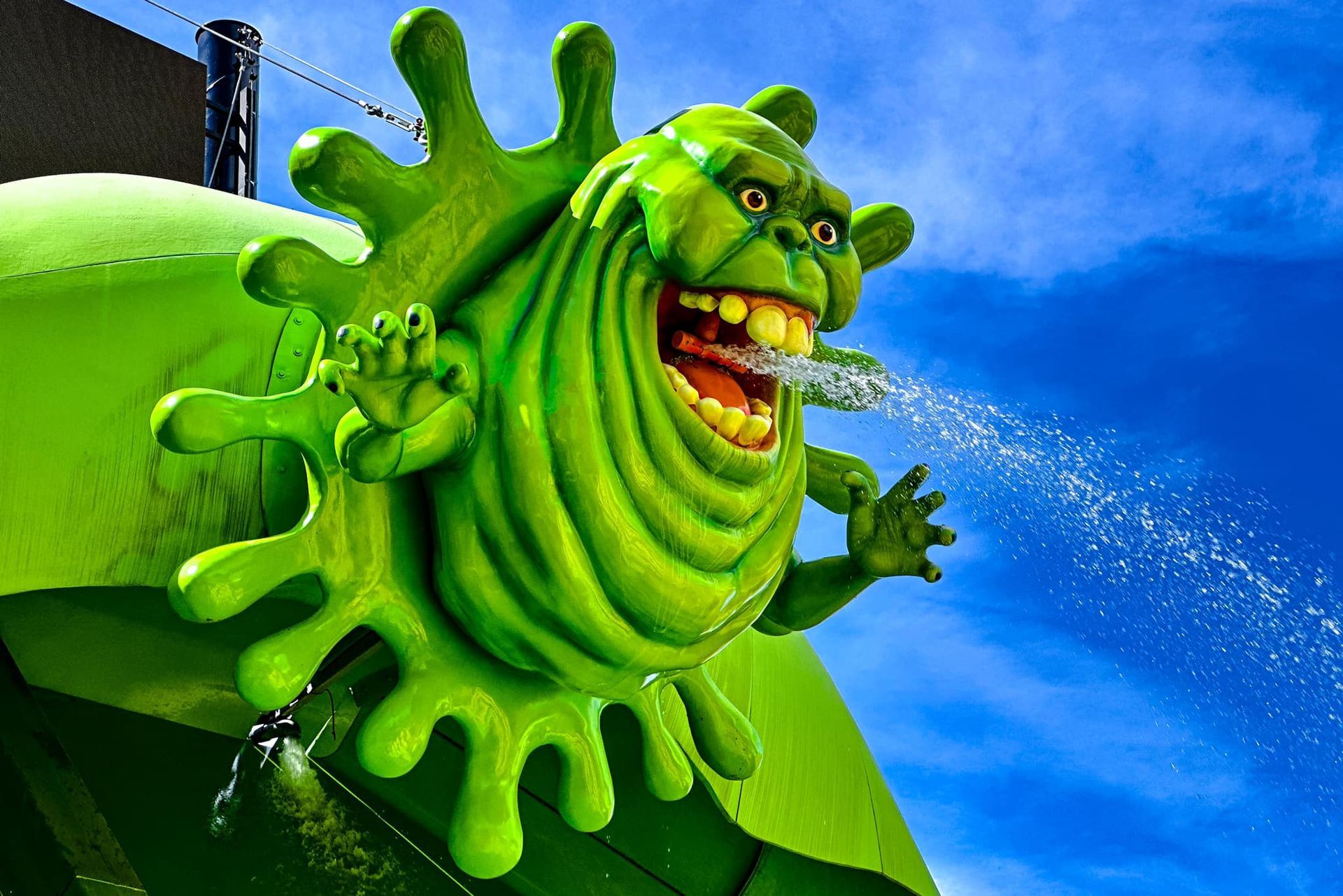 A statue of a green monster spraying water from its mouth.