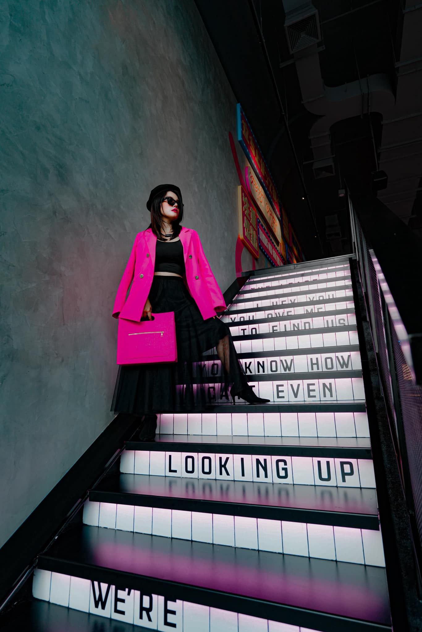 A woman in a pink coat is standing on a set of stairs.