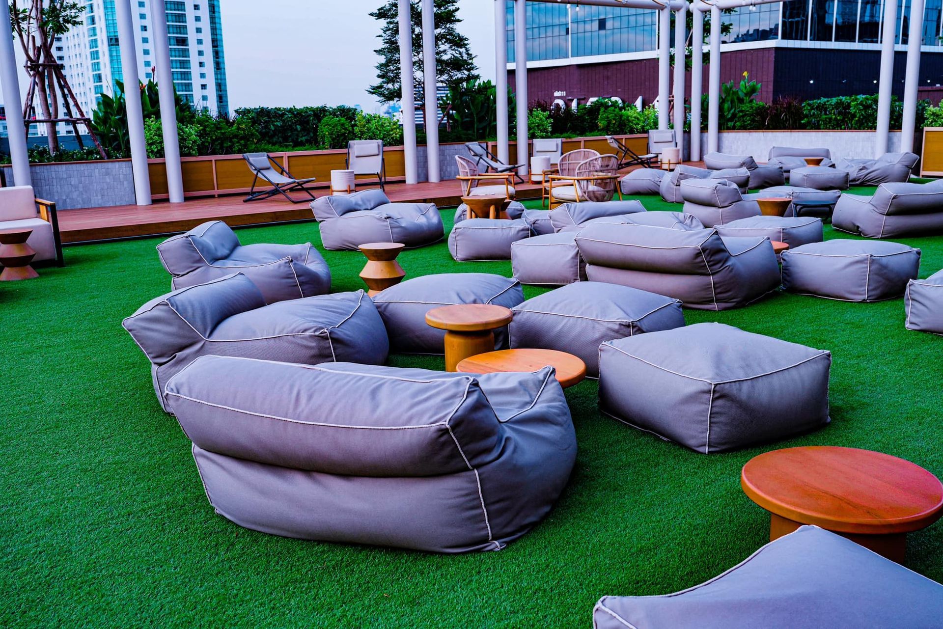 There are many bean bag chairs and tables on the grass.