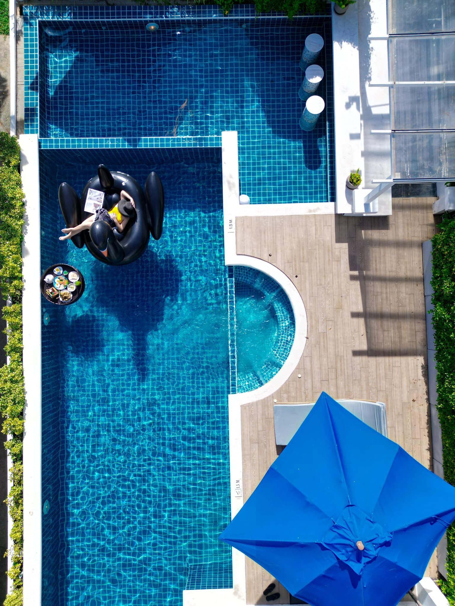 An aerial view of a swimming pool with a blue umbrella