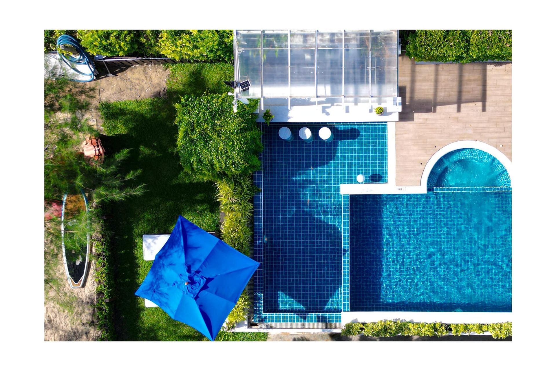An aerial view of a house with a swimming pool and a blue umbrella.