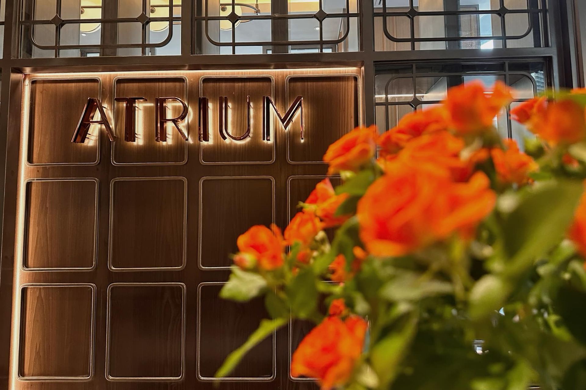 A bunch of orange flowers are in front of a sign that says atrium
