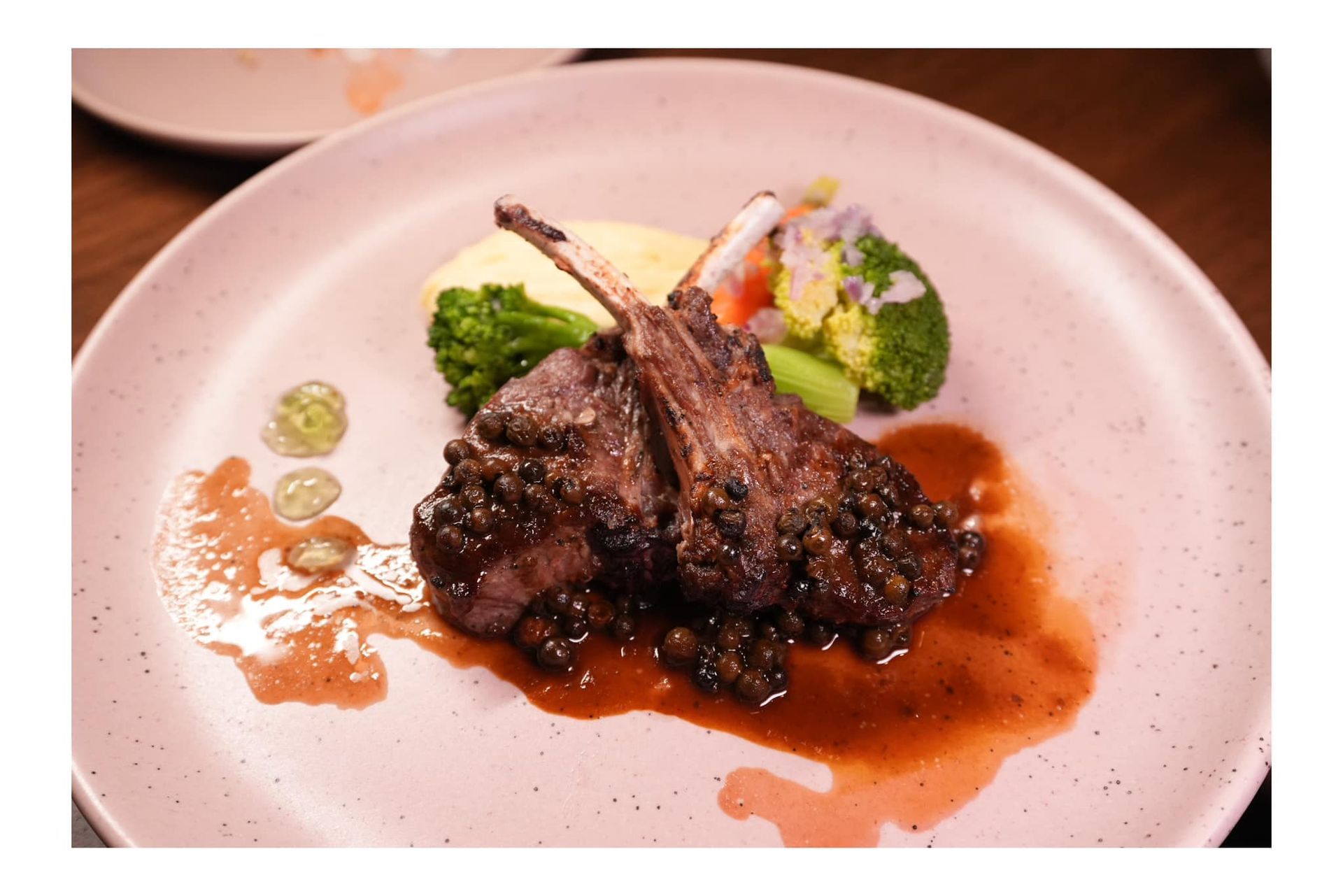 A close up of a plate of food with meat and vegetables on a table.