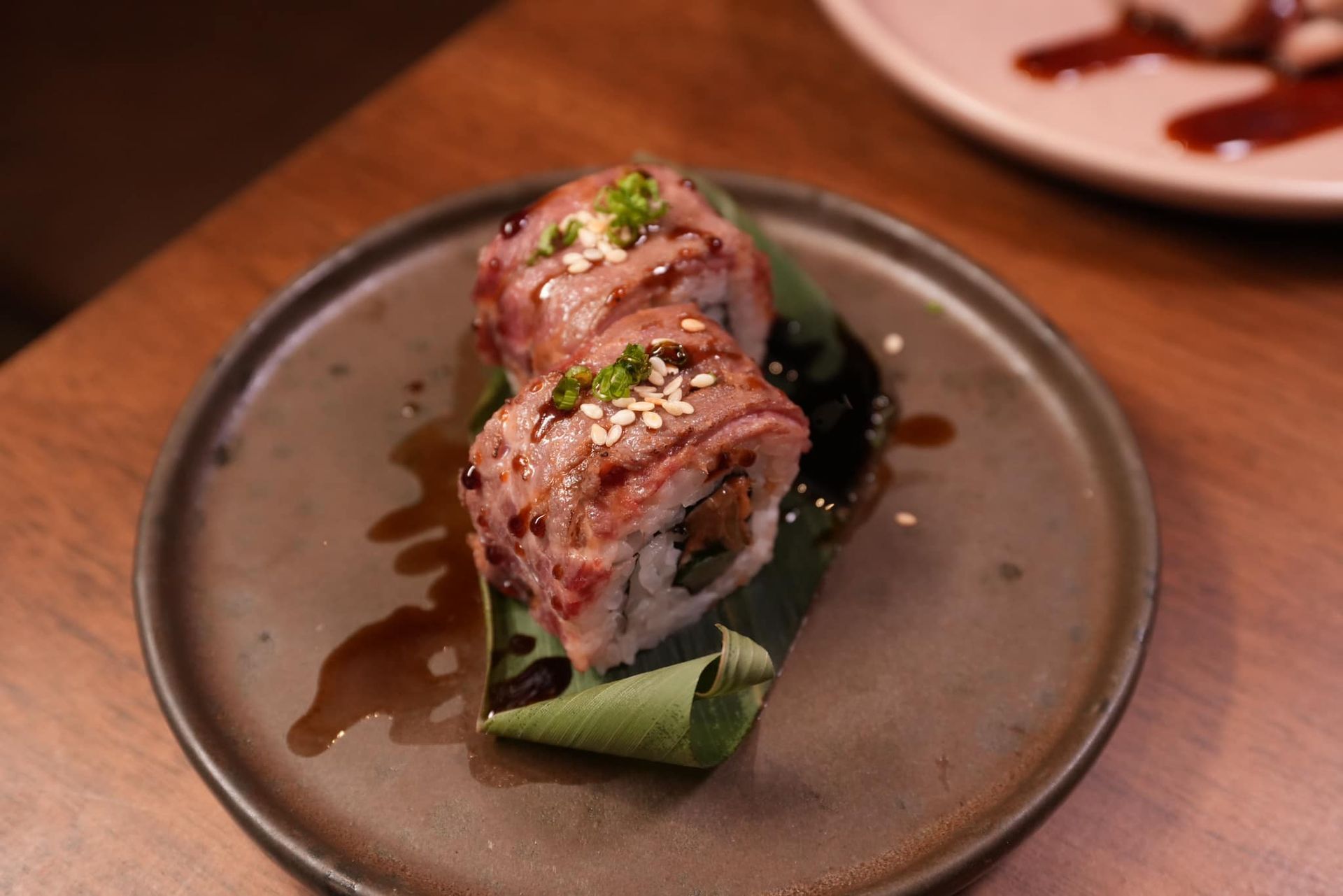 A close up of a plate of sushi on a wooden table.