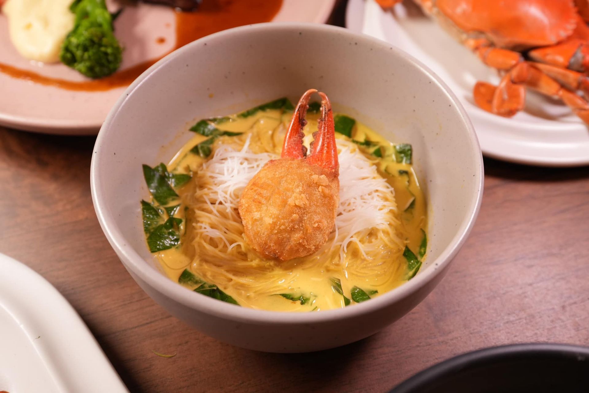 A bowl of food with a crab claws in it on a table.