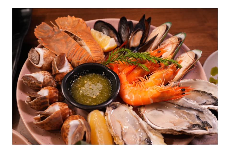 A plate of seafood with sauce on a wooden table  at Atrium Restaurant.