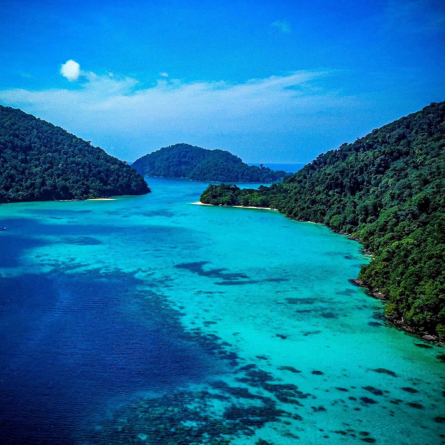 A large body of water surrounded by mountains and trees in Surin Islands