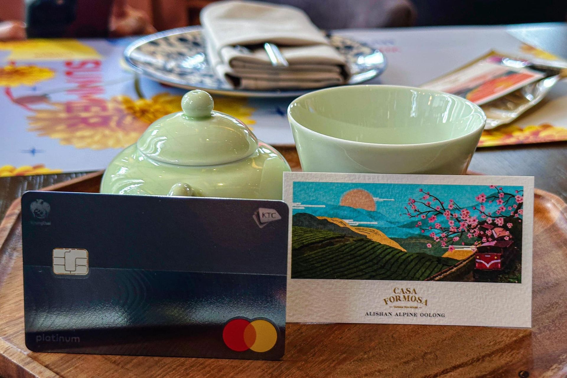 TheKTC credit card is sitting on a wooden tray next to a cup of tea.